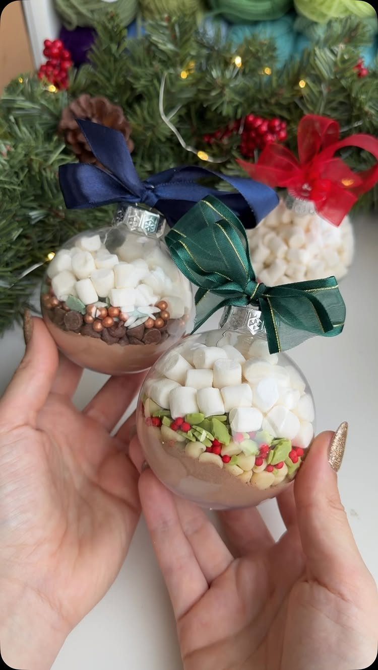 Hot chocolate mix in round ornament jars with marshmallows and colorful ribbons.