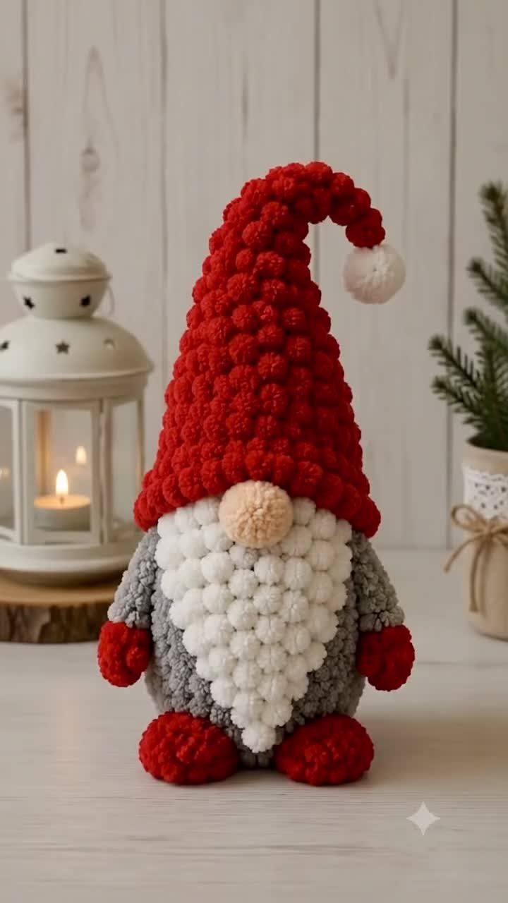 Pom-pom gnome figure with a red hat and white beard next to a lantern.