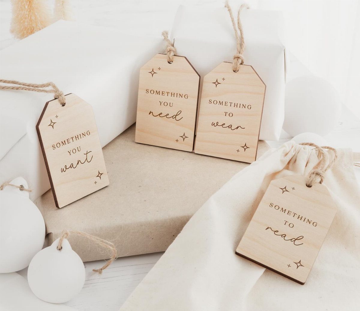 Wooden gift tags with engraved text and twine strings on wrapped presents.