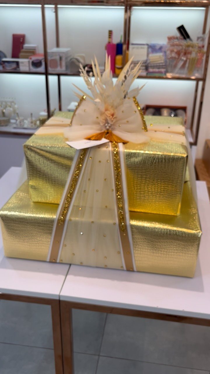 Two gold metallic wrapped gift boxes with sheer ribbons and a decorative bow.