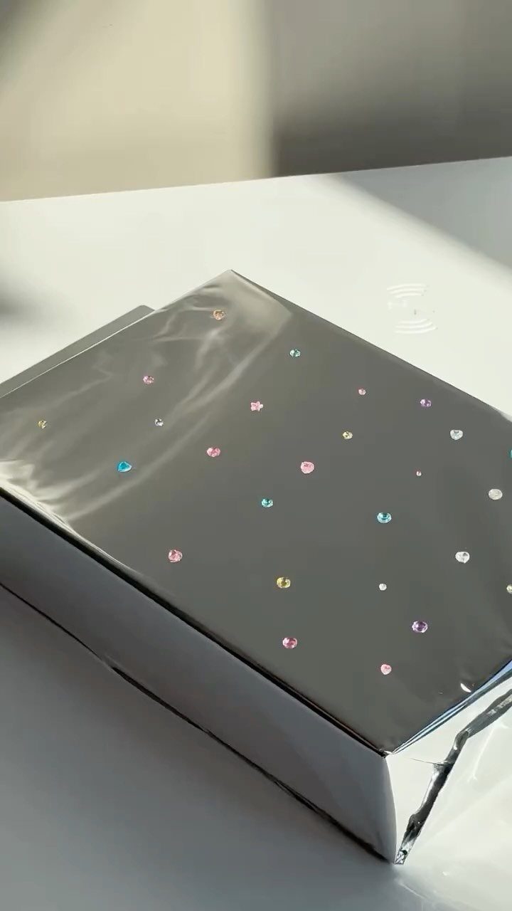 Silver metallic wrapped gift with small colorful iridescent dots on a white surface