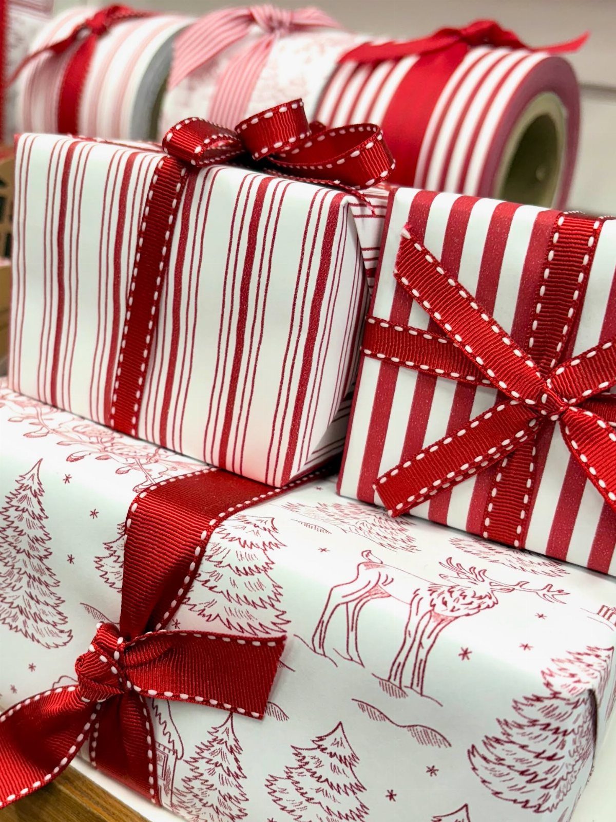 Wrapped gifts with red and white stripes and reindeer patterns tied with red ribbons.