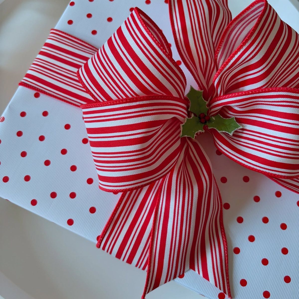 White gift wrapped in red polka dot paper with a striped red ribbon bow.