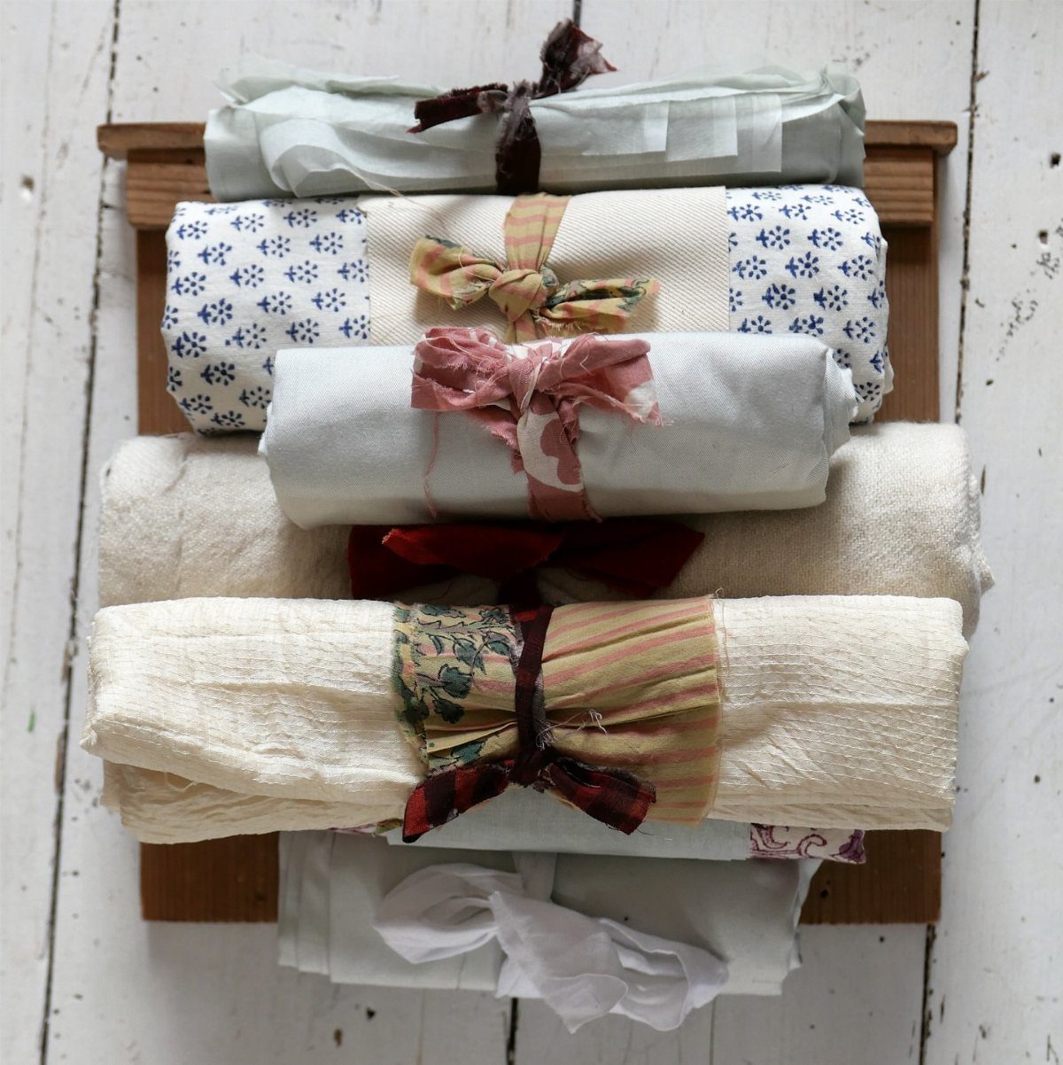 Fabric wrapped gifts tied with ribbons stacked on a rustic wooden surface