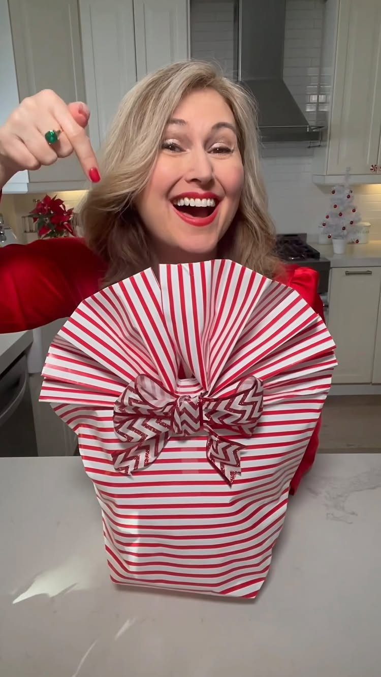 Woman holding a red and white striped gift wrapped without a box.