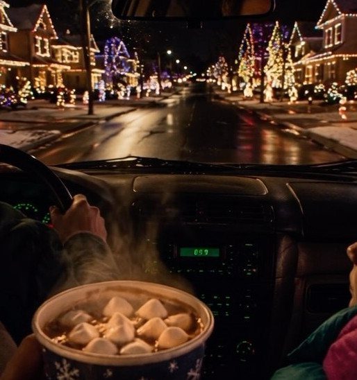 View from a car dashboard showing a street lined with festive Christmas lights.