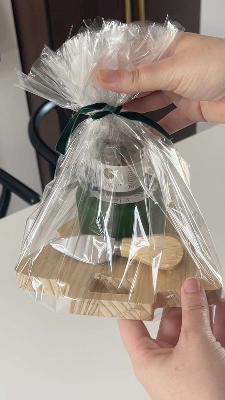 Gift set with wooden board and cheese knife wrapped in clear cellophane