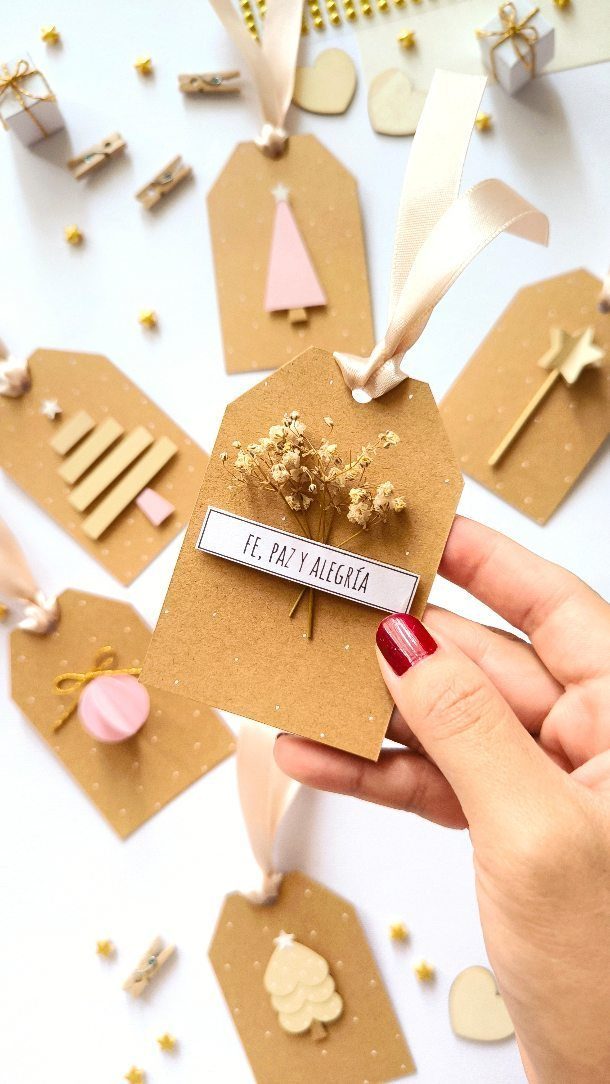 Hand holding a handmade brown paper gift tag decorated with dried flowers