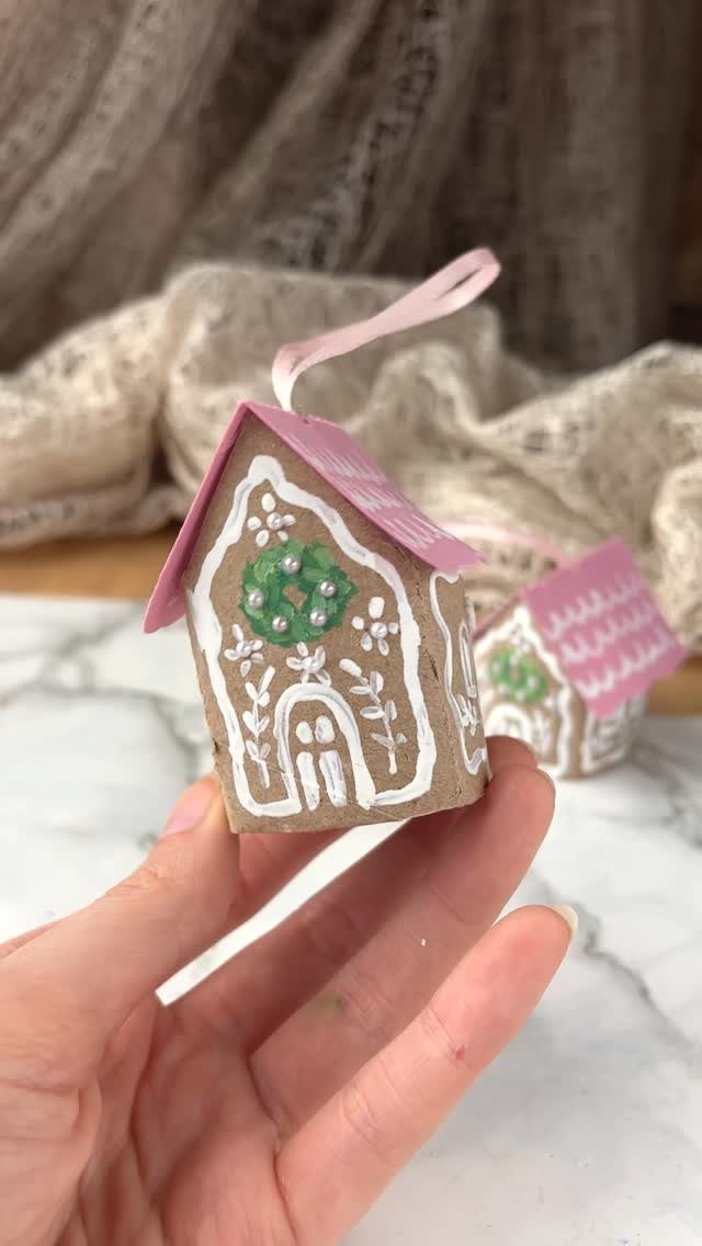 Handmade paper house ornament with pink roof and white icing decorations.