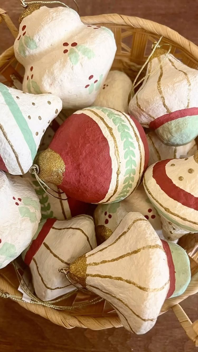 Handmade paper Christmas ornaments in a wicker basket with gold and red accents.