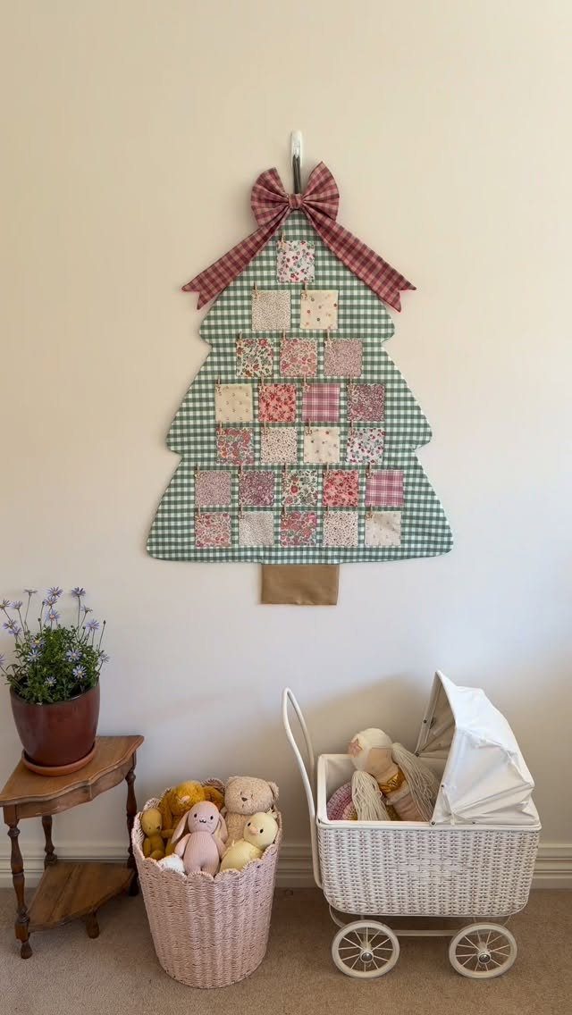 Fabric Christmas tree wall hanging with patchwork squares and a red checkered bow.