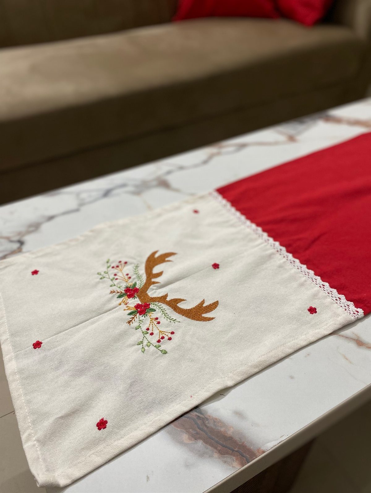 Festive table runner with red and white fabric and embroidered reindeer antler design.
