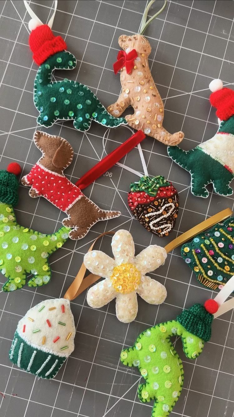 Handmade felt ornaments with sequins and beads on a grey cutting mat.