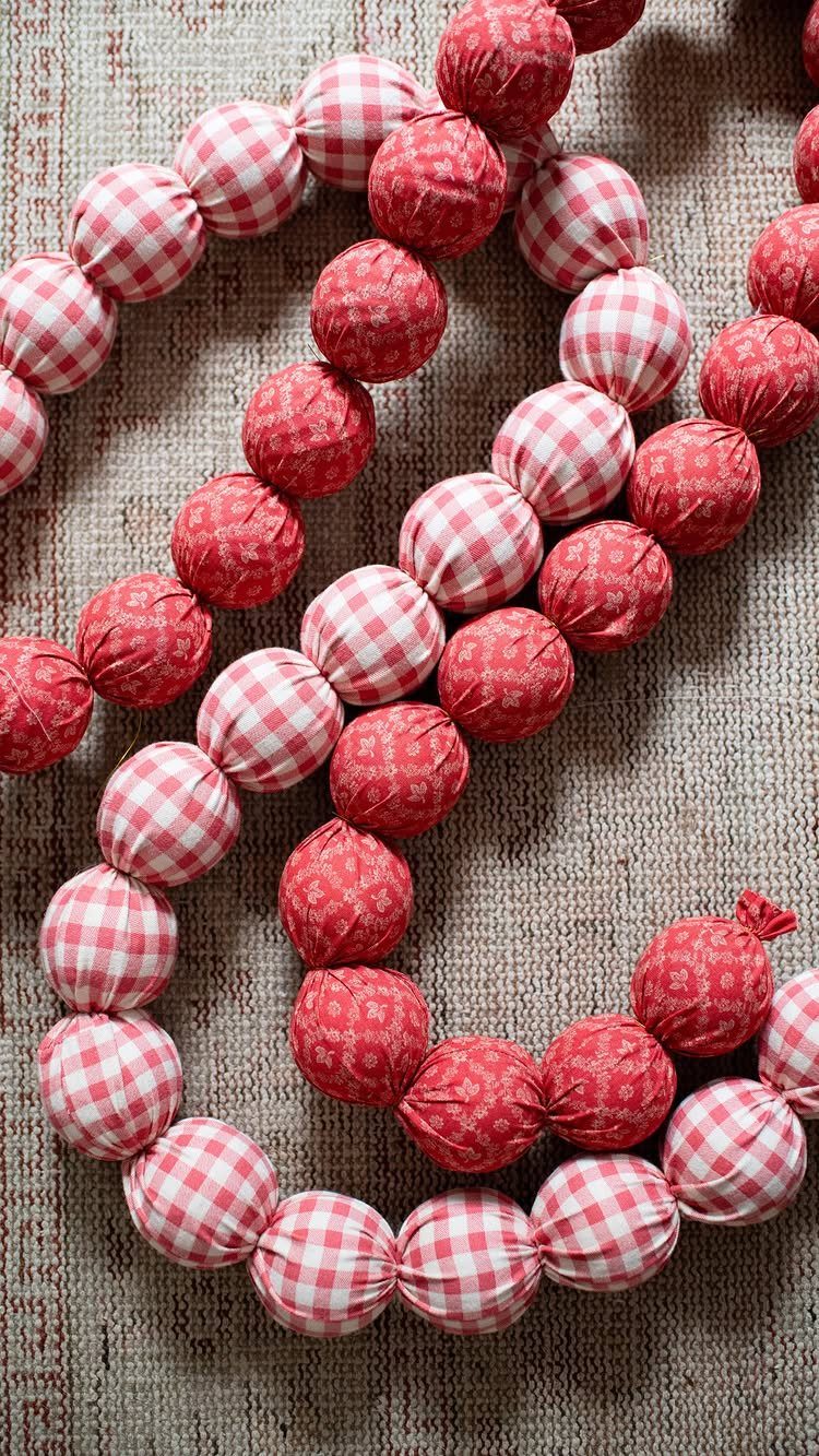 Red and white checkered fabric ball garland on a neutral textured background