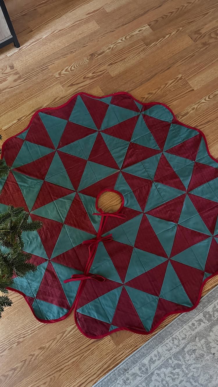 Quilted Christmas tree skirt with red and teal geometric triangles on wooden floor