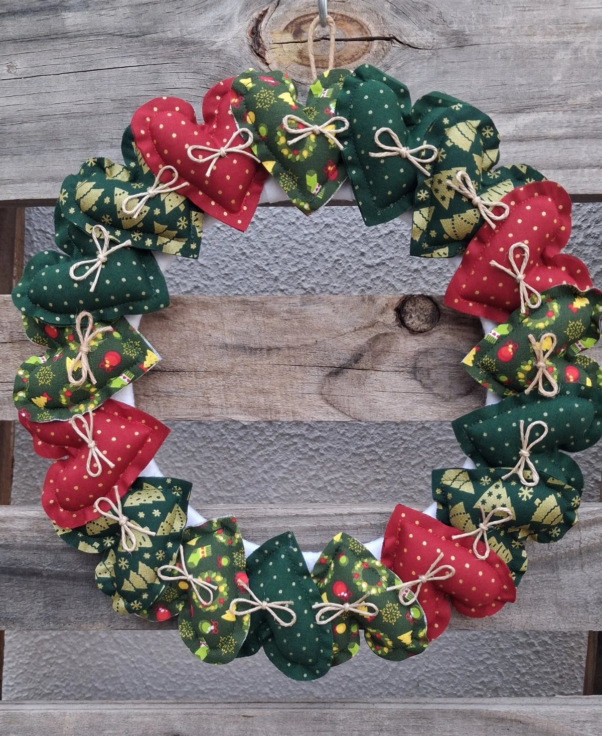 Fabric wreath made of red and green patterned hearts tied with twine.