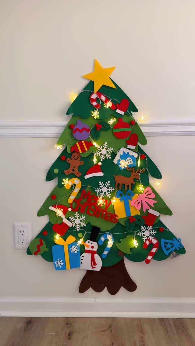 Felt Christmas tree on a wall decorated with colorful felt ornaments and fairy lights