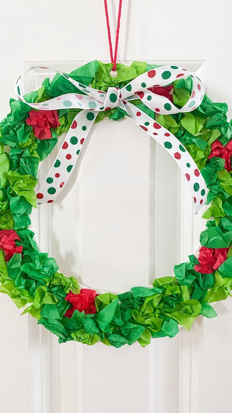 Tissue paper Christmas wreath with a polka dot ribbon hanging on a white door