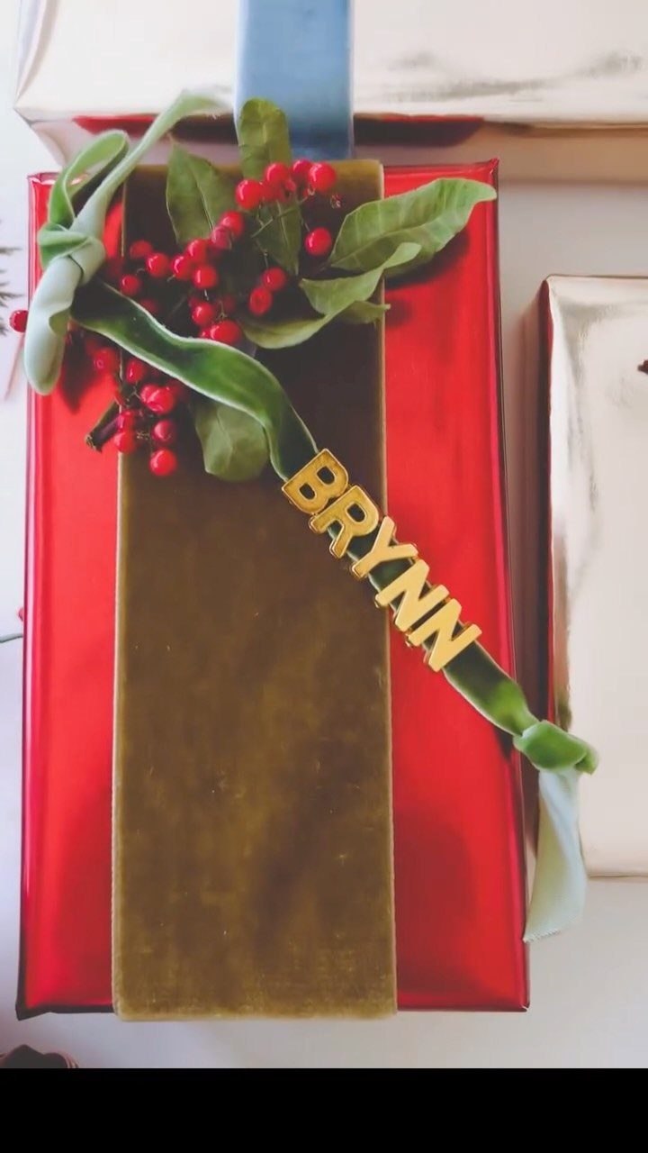 Red wrapped gift with green velvet ribbon, red berries, and gold BRYNN name tag.