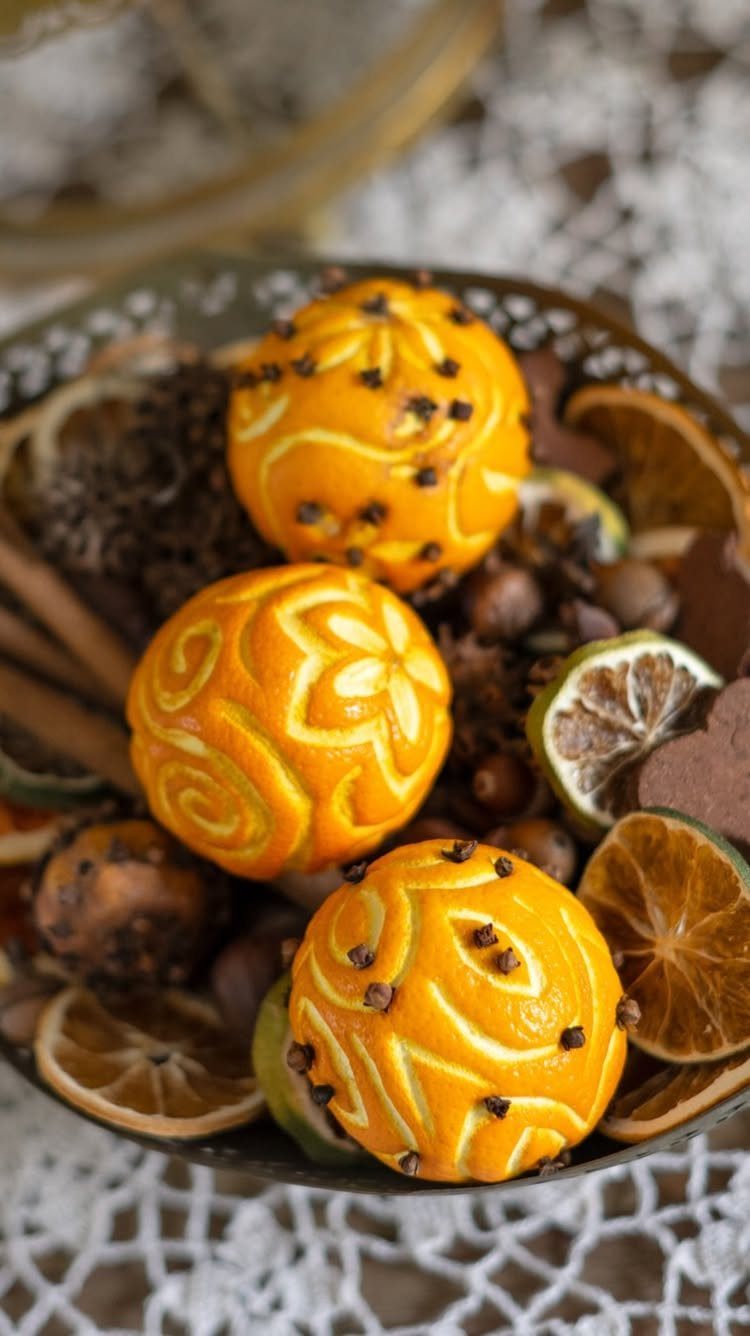 Carved oranges with cloves and dried citrus slices in a decorative bowl