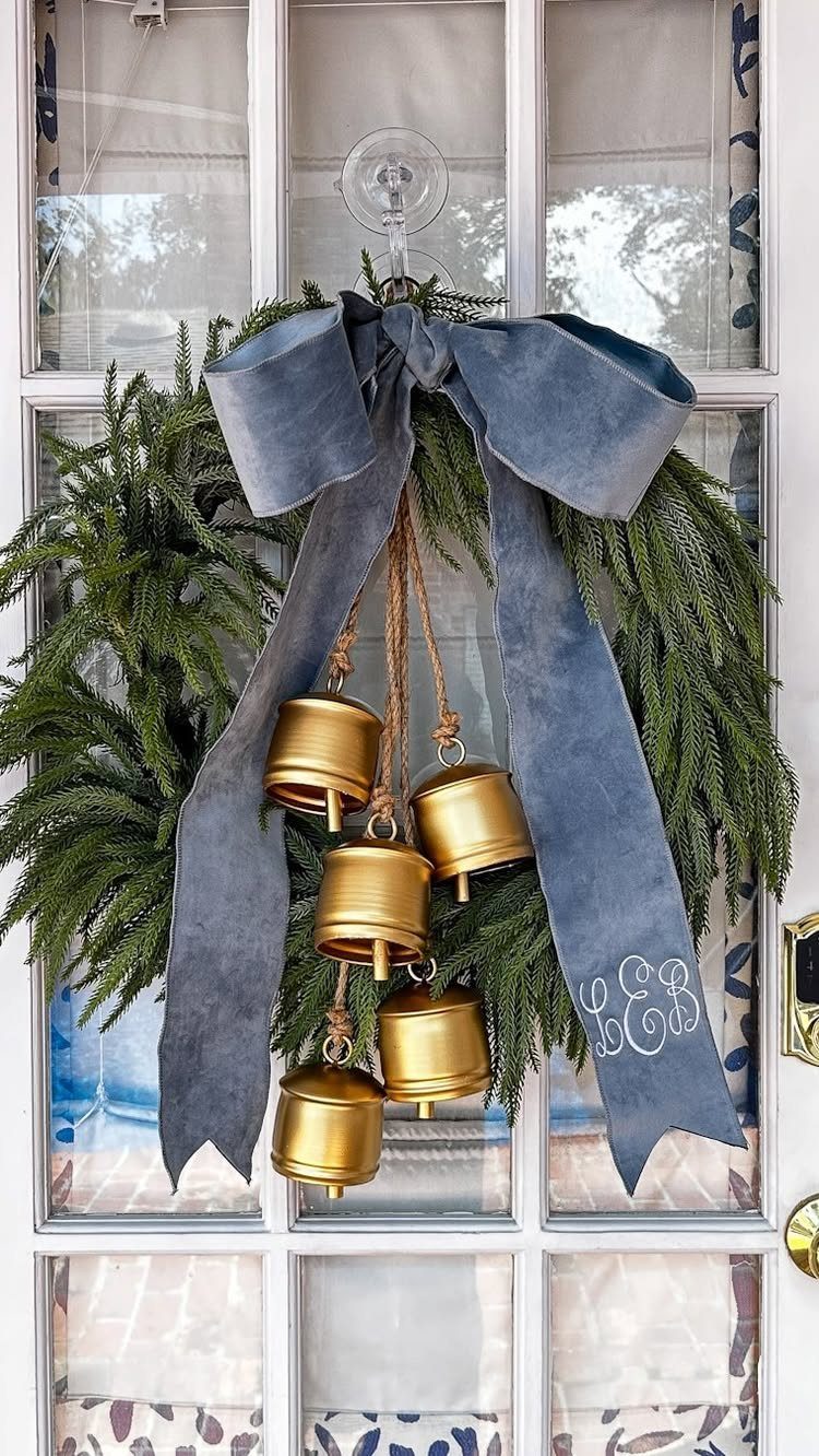 Evergreen wreath with a blue velvet bow and hanging gold bells on a door