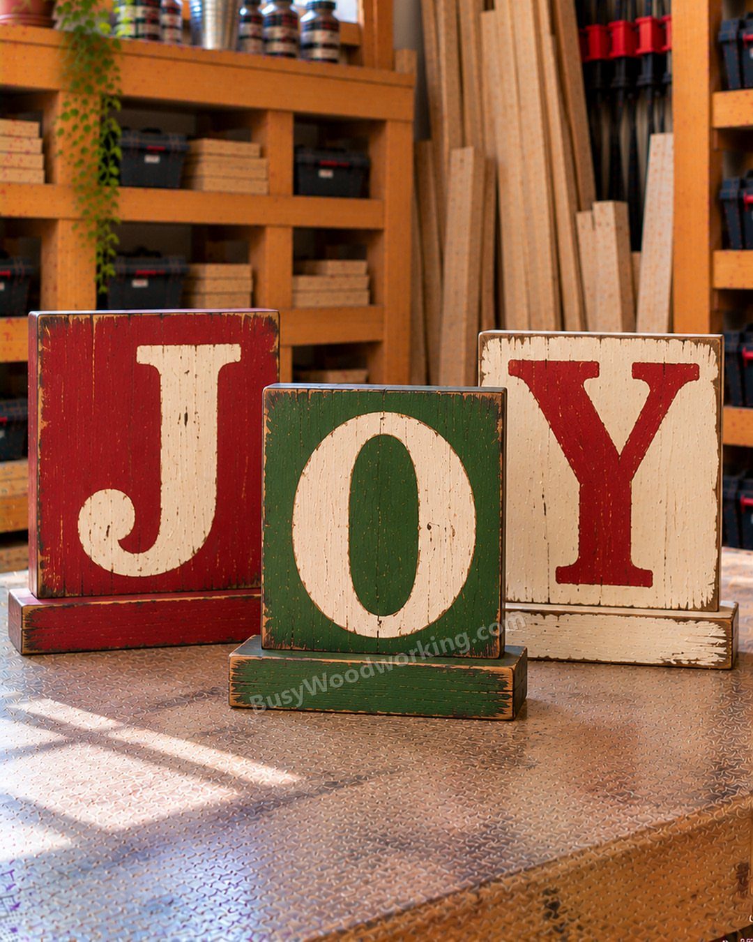 Wooden blocks spelling JOY in red, green, and white rustic paint on workbench