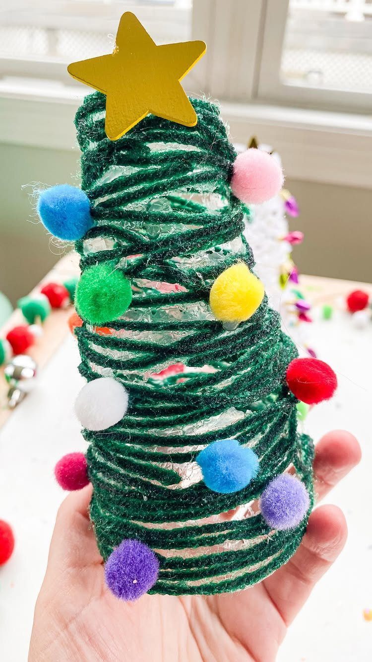 Small green glittery pipe cleaner Christmas tree decorated with colorful pom-poms and star