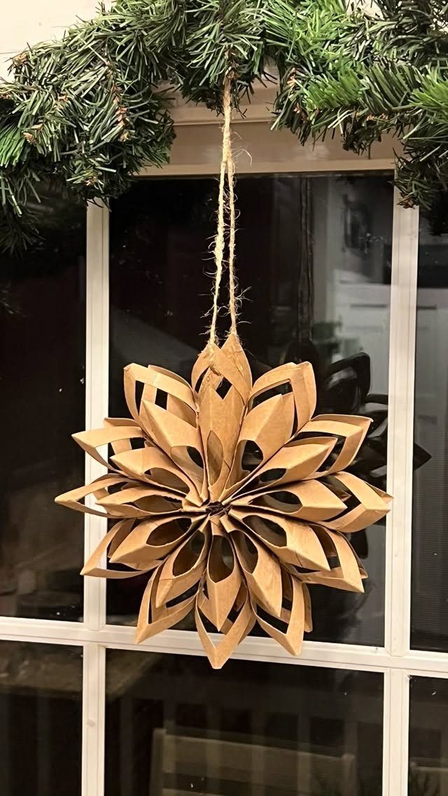Cardboard star ornament made from toilet paper rolls hanging from a pine garland.