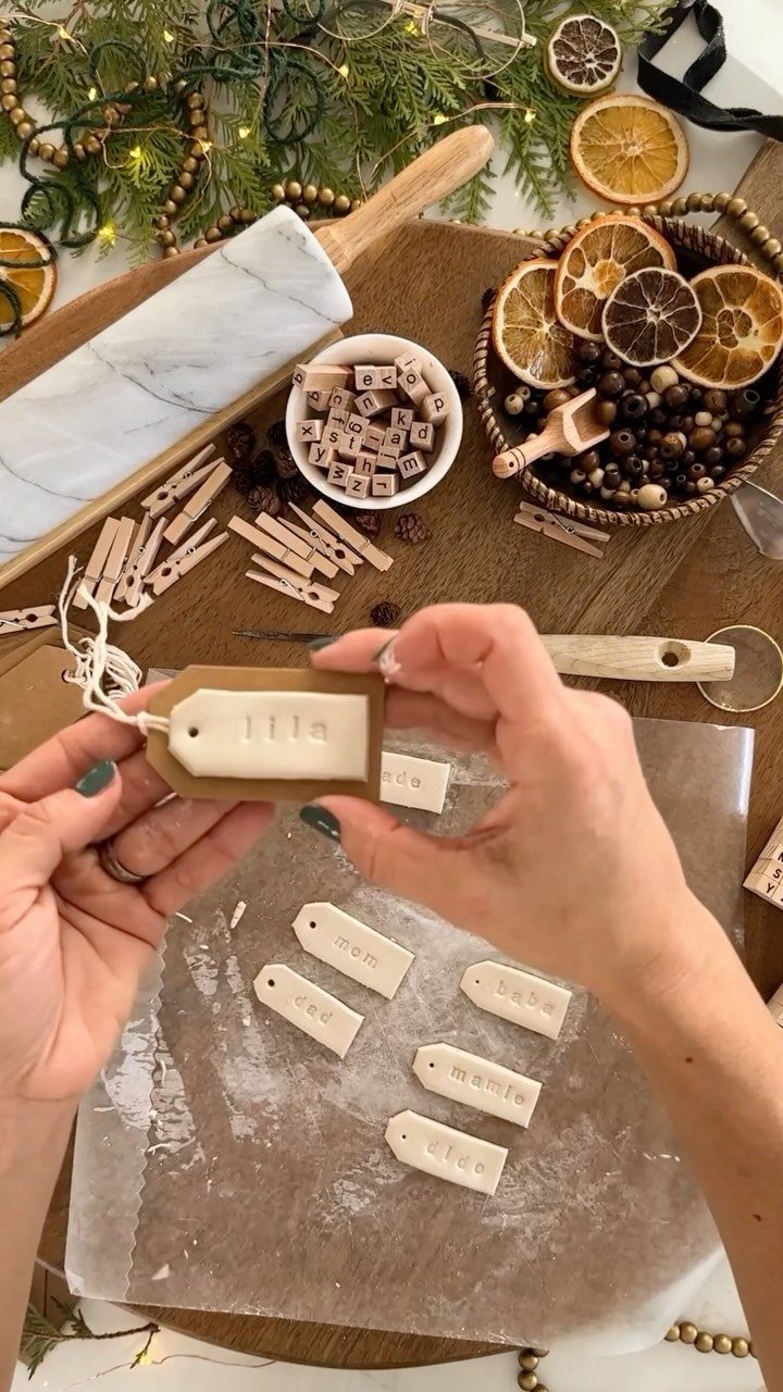 Hands holding a stamped white air-dry clay gift tag on a wooden table.