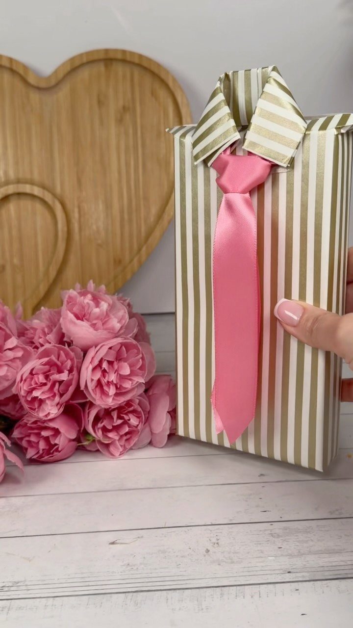 Striped gift wrap styled as a shirt with a pink ribbon tie and peonies.