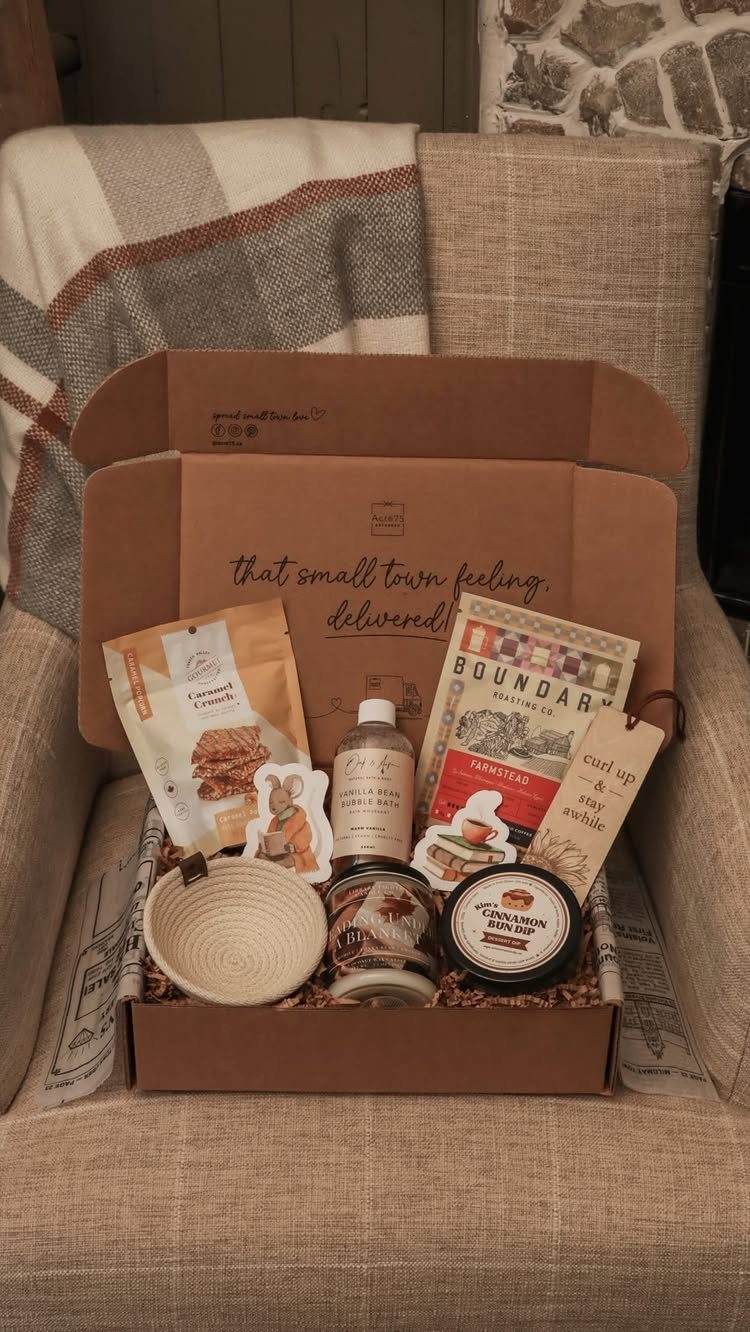 Gift box containing gourmet snacks, a small bowl, and a booklet on a chair.