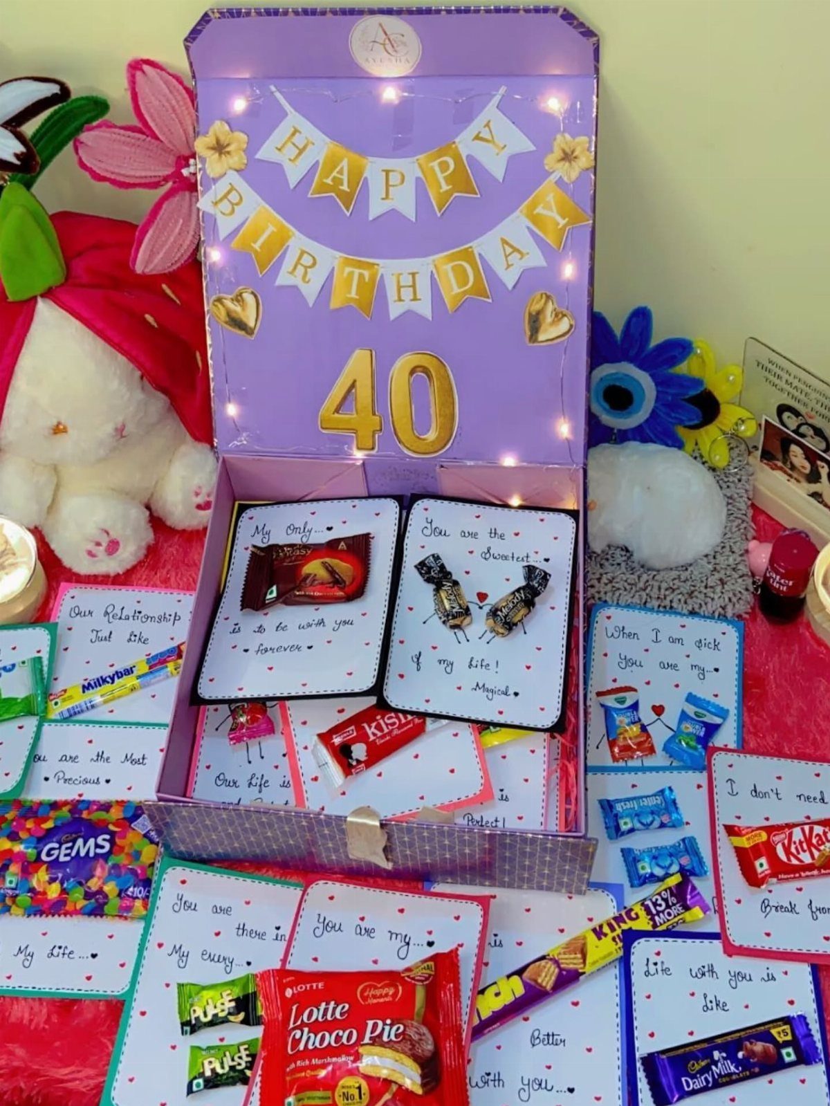 Purple birthday explosion box with chocolates, handwritten notes, and candies for a 40th birthday.