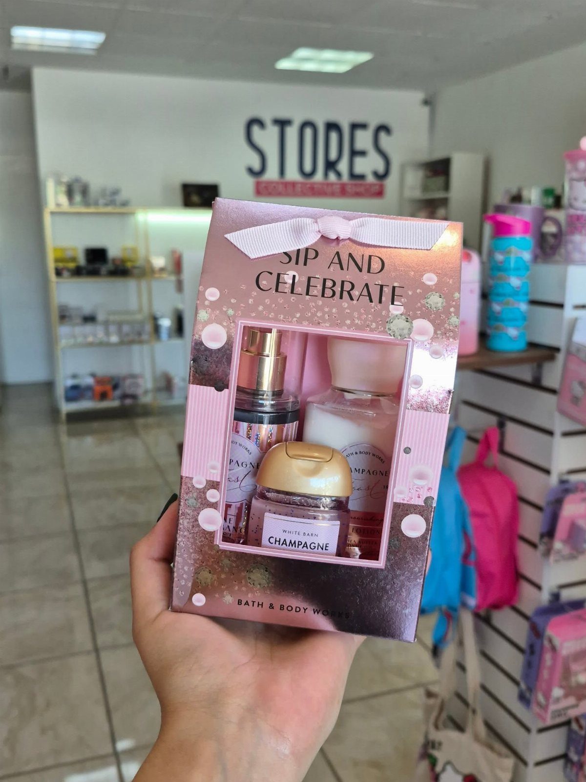 Pink gift set box with lotion and candle held in a hand.