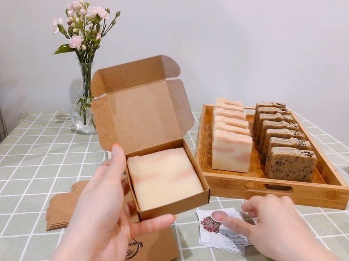 Handmade soap bars in a wooden tray and a small gift box.