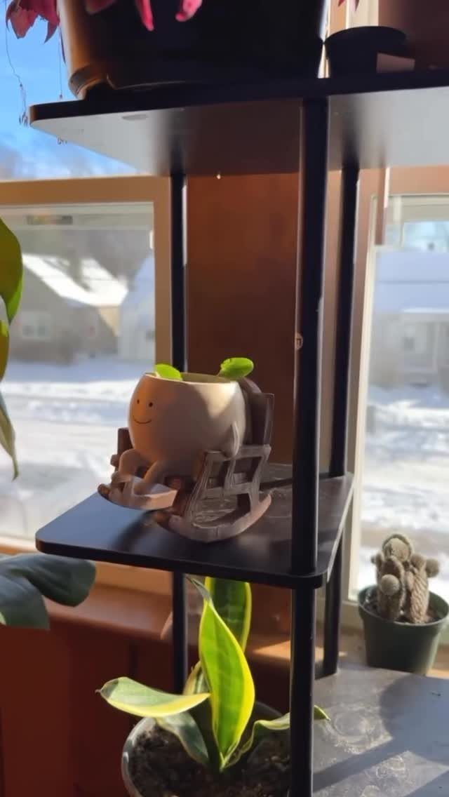 Smiley face ceramic planter sitting in a tiny wooden rocking chair on a shelf
