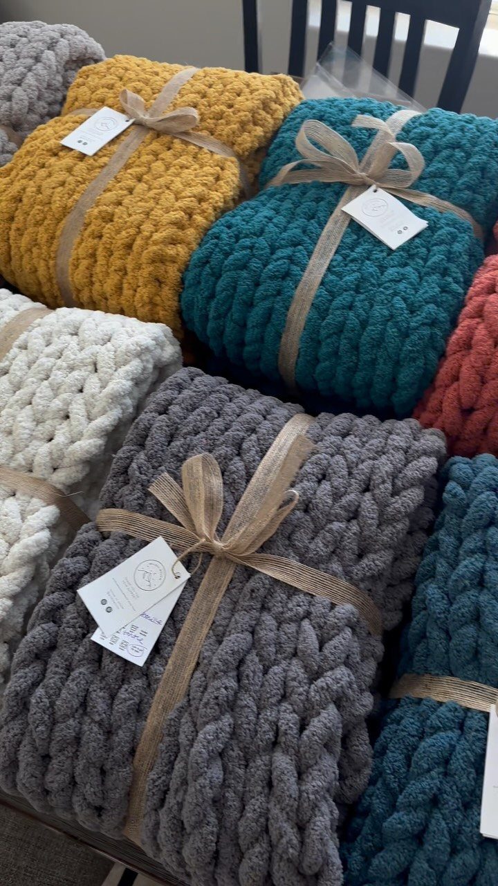Chunky knit blankets in various colors tied with ribbons and gift tags.