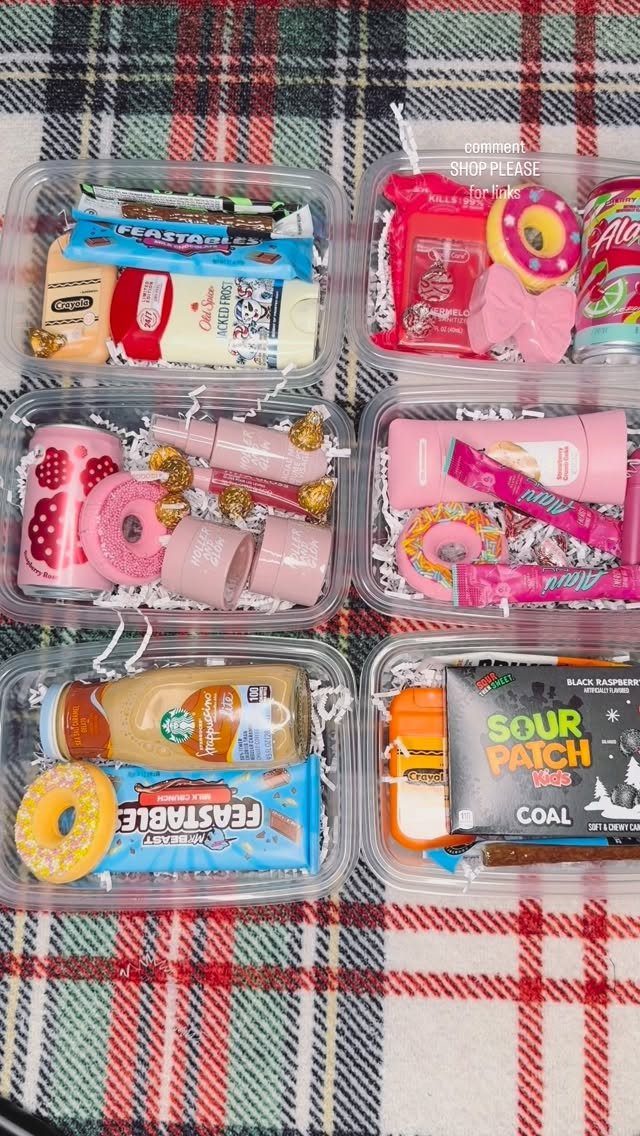 Six clear gift bins filled with colorful snacks and beauty products on plaid fabric.