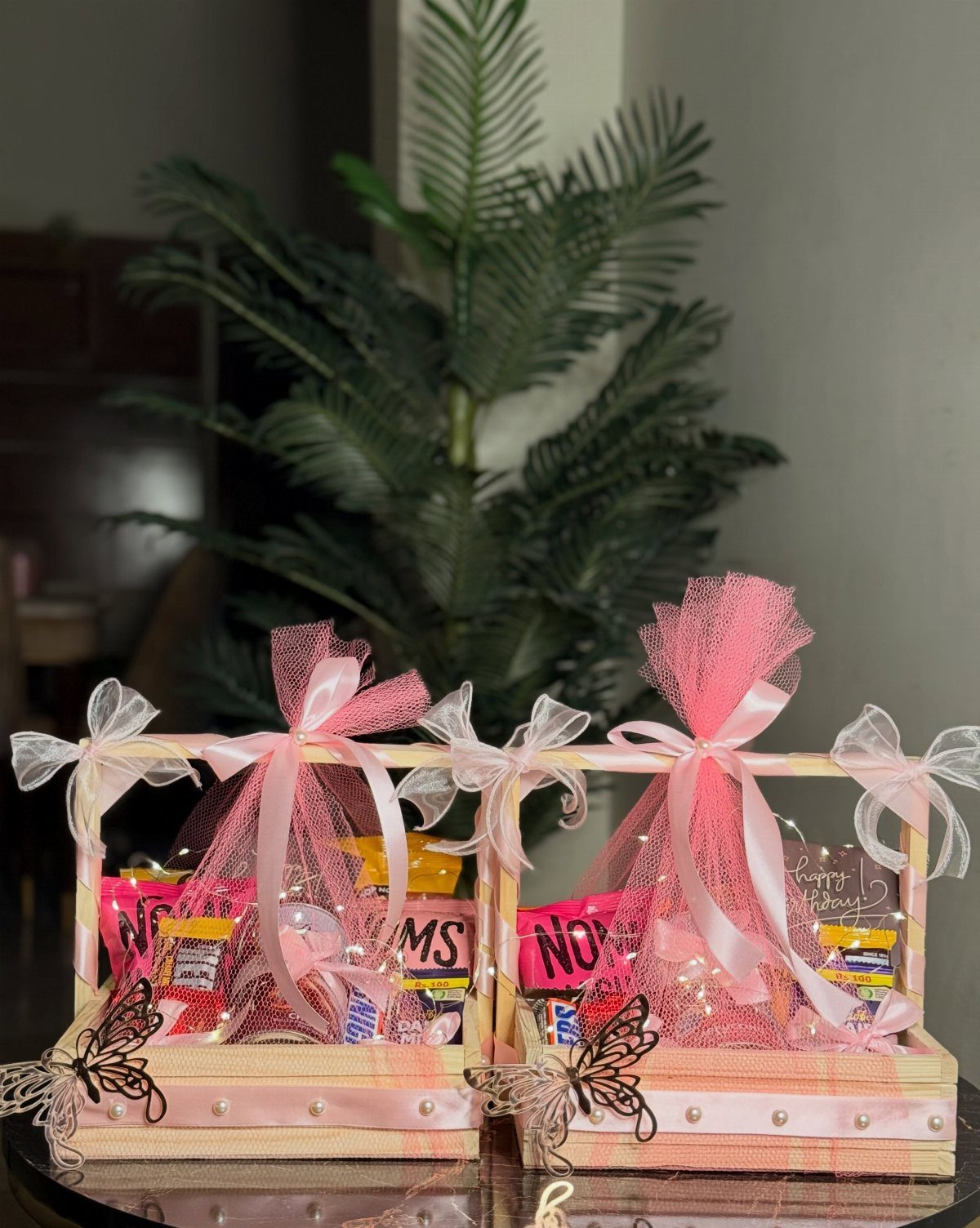 Two small wooden gift baskets filled with candies and wrapped in pink tulle.