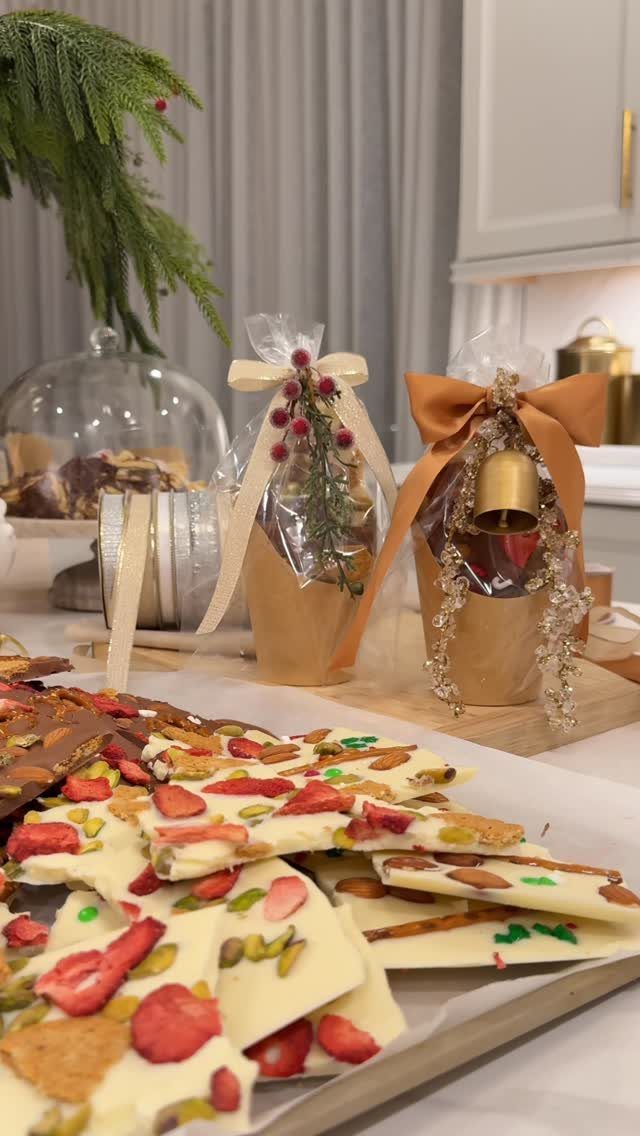 White chocolate bark with strawberries and pistachios next to wrapped gift bags.