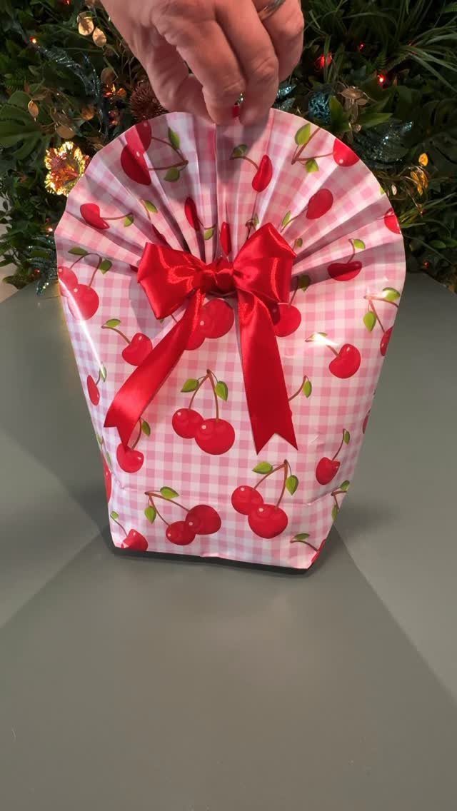 Gift wrapped in pink cherry patterned paper with a red satin bow.