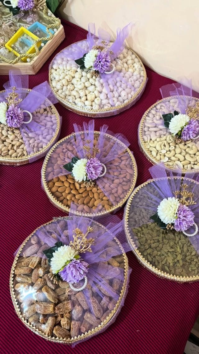 Round gift containers filled with dried fruits and nuts decorated with purple bows.
