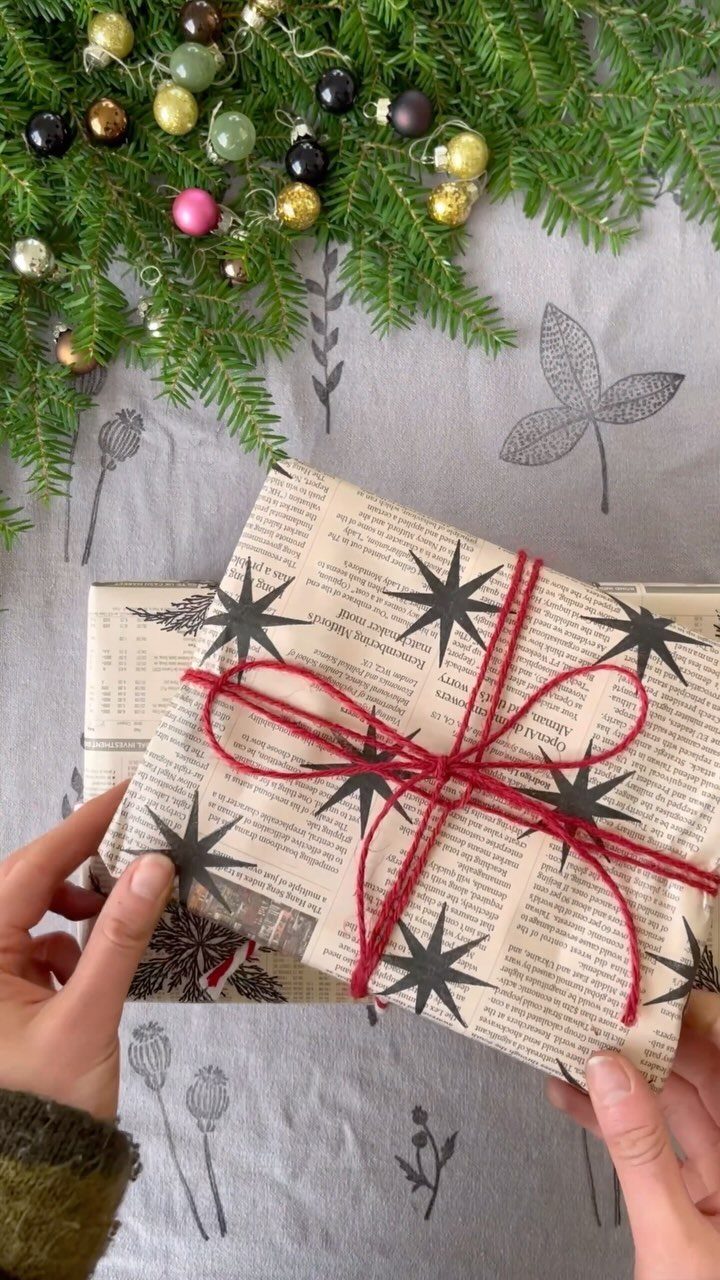 Gift wrapped in newspaper paper with black stars and a red string bow.