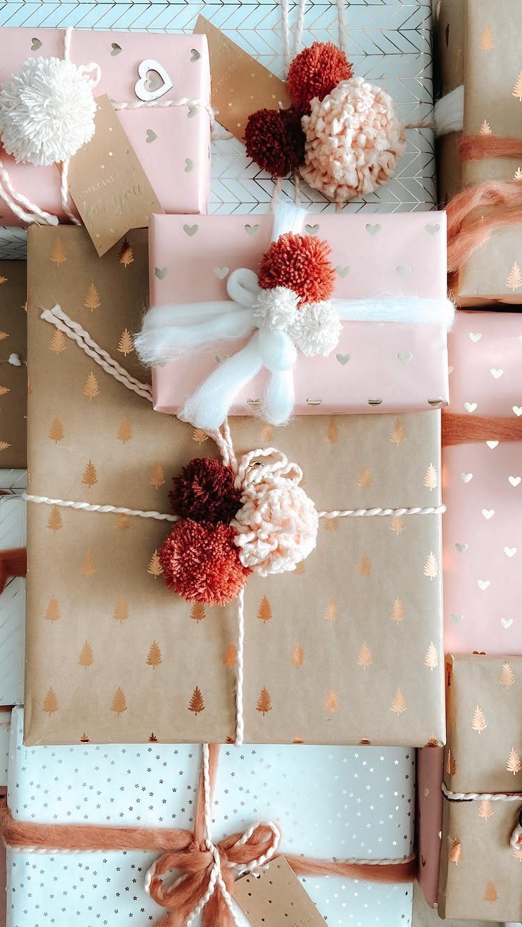 Wrapped gifts in pink and brown paper decorated with colorful fluffy pom poms.