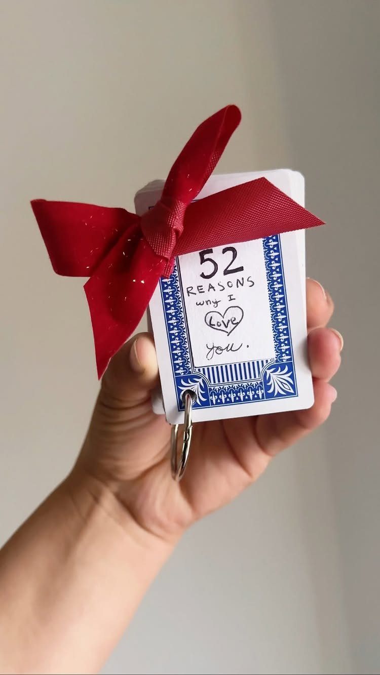 Hand holding a deck of 52 reasons why I love you cards with ribbon.