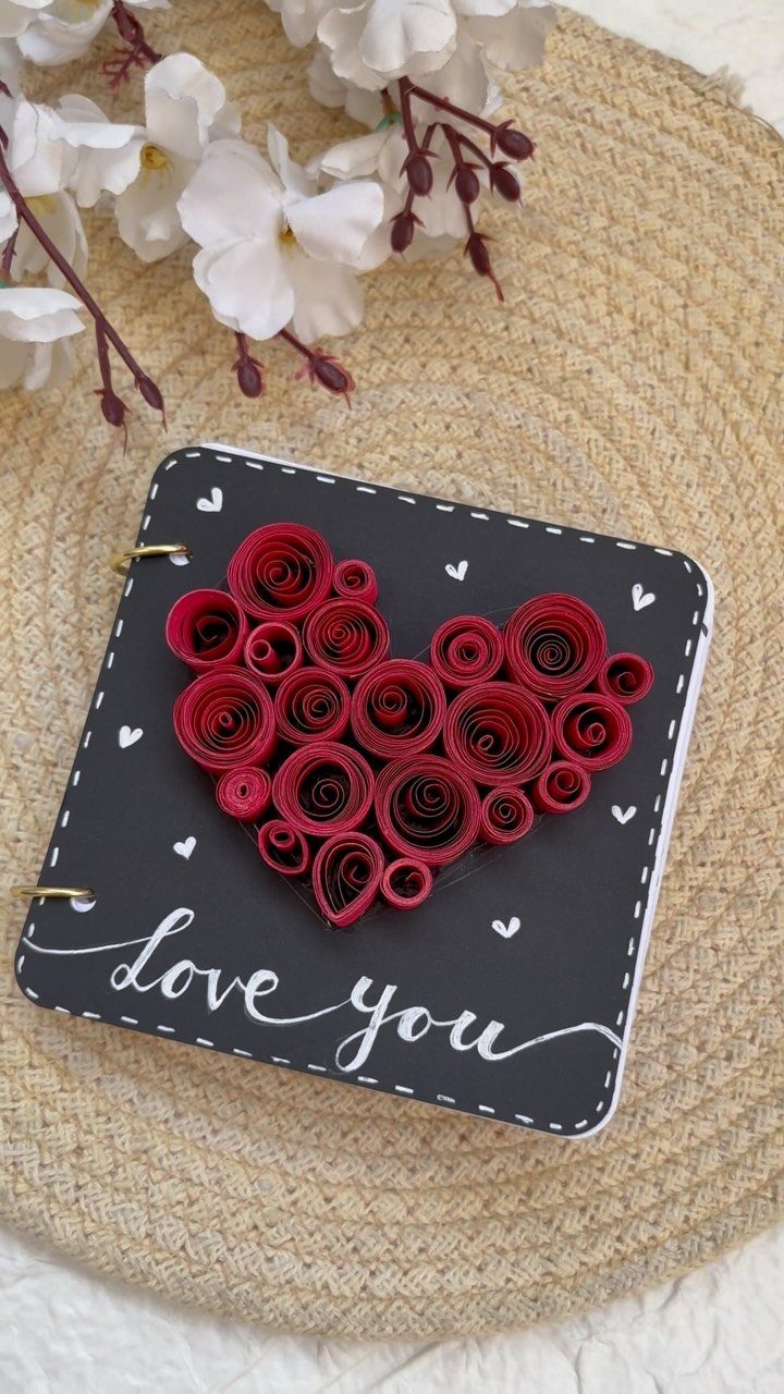 Black handmade scrapbook with a red quilled paper heart and love you text.