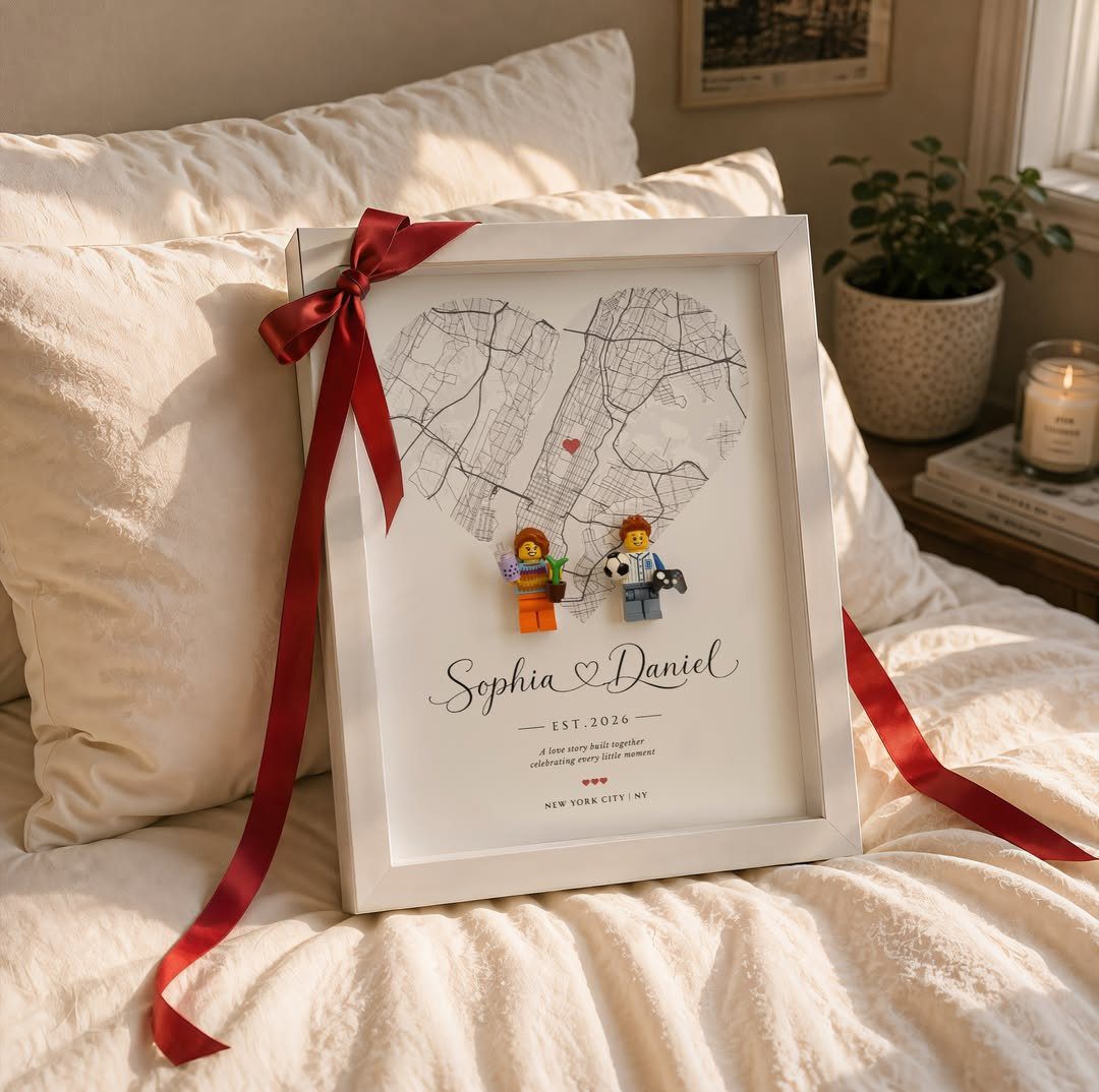 Framed heart-shaped city map with LEGO figures and names on a white bed