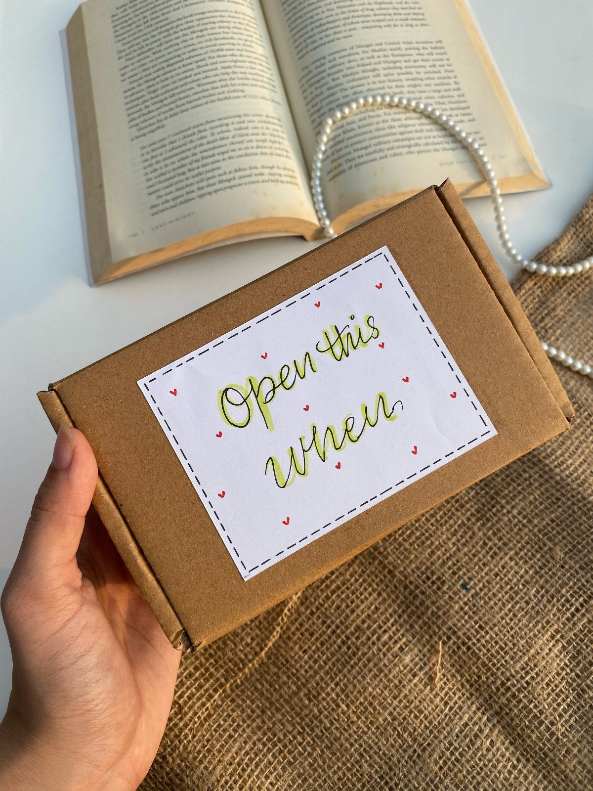 Brown cardboard box with Open this when label held over an open book.