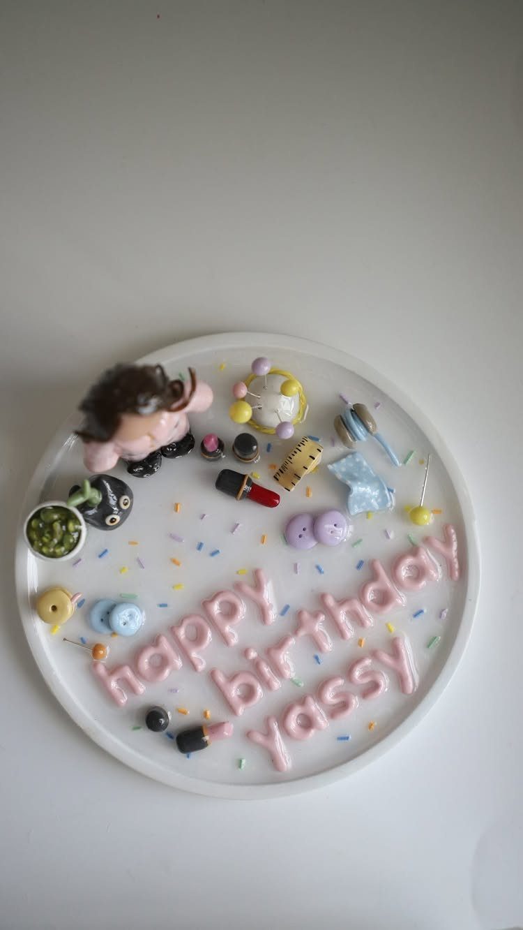 White clay trinket dish with pink birthday lettering and miniature colorful accessories.
