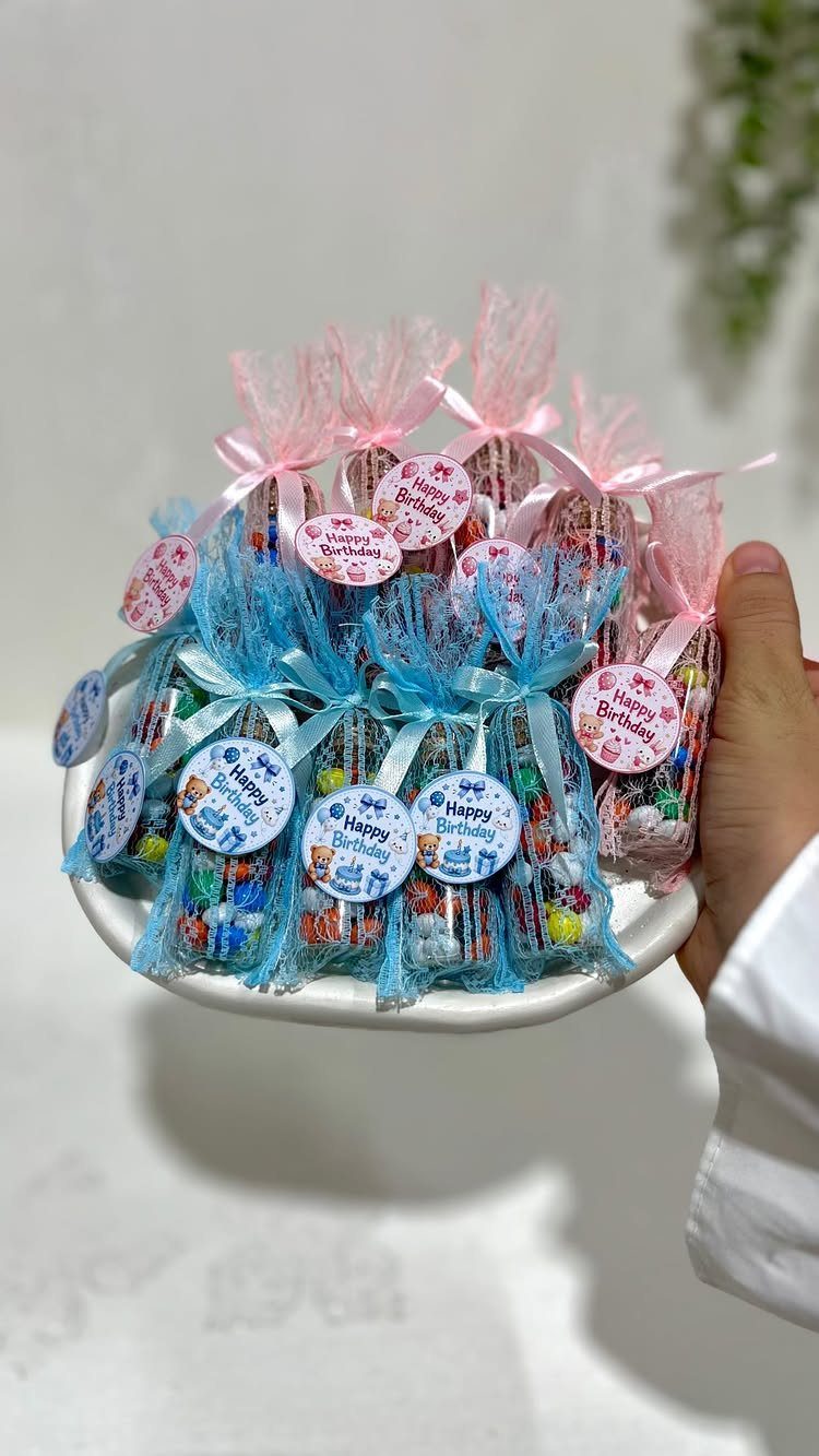 Small glass jars filled with colorful candies tied with tulle ribbons and birthday tags.