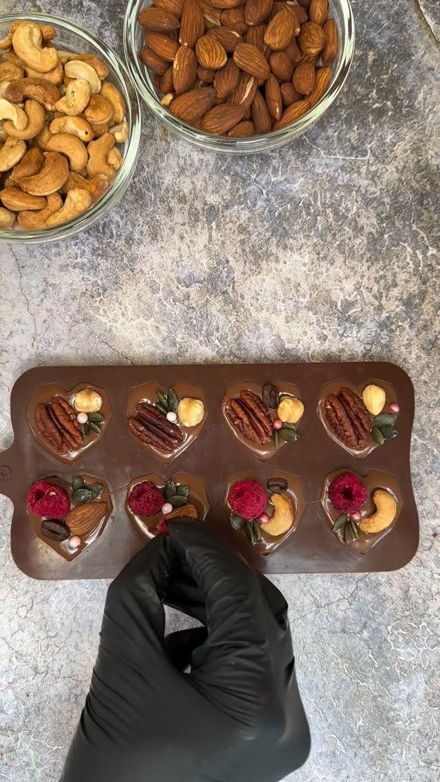 Heart-shaped chocolates with nuts and berries in a silicone mold with almond bowls.